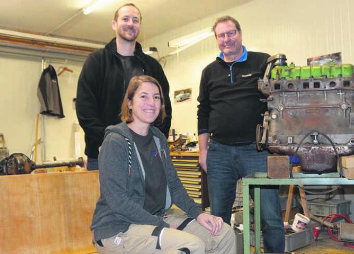 Die Sitzbank, auf der Jolanda Hofmann sitzt, wurde bereits abgeschliffen. Auch der Motor wird überarbeitet. Michael Baur, Präsident des Feuerwehrvereins Waltenschwil (links), und Pirmin Imboden sind mit dem Verlauf der Restauration bisher zufrieden. Bilder: Sabrina Salm / zg