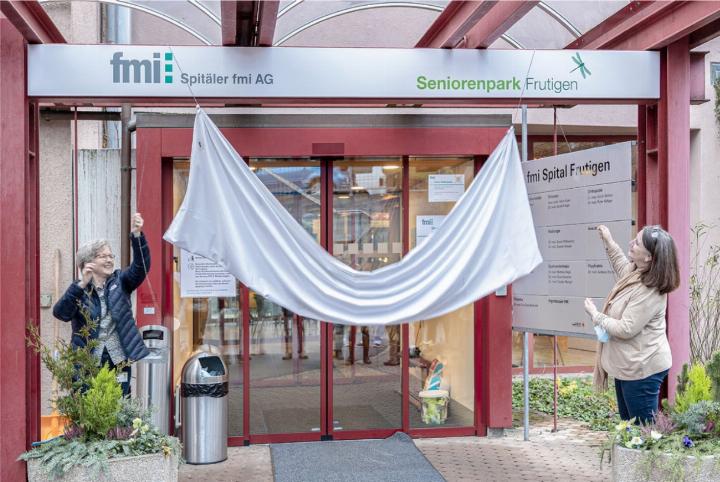 Doris von Känel vom Seniorenpark Frutigen (links) und fmi-CEO Daniela Wiest enthüllen das neue Logo beim Haupteingang zum Spital und zum Seniorenpark Frutigen. BILD: ZVG / FMI AG