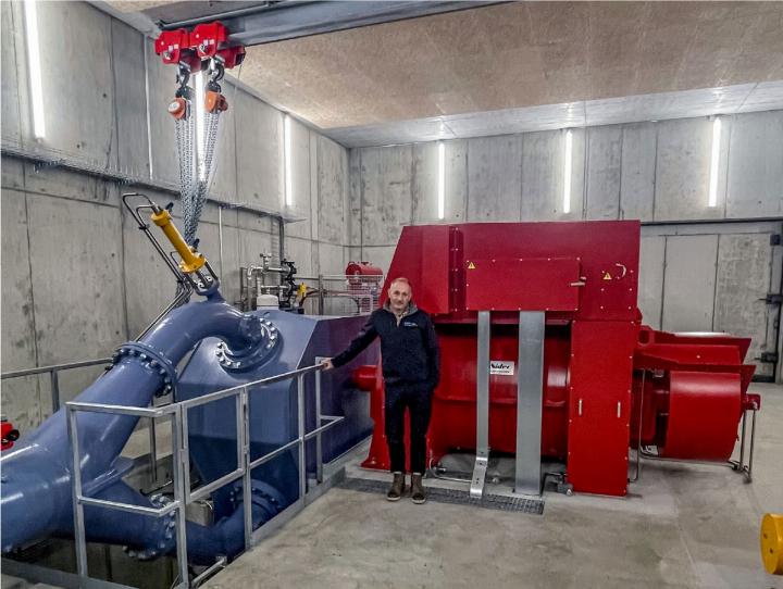 LWK-Geschäftsleiter Reto König präsentiert im Kraftwerkinnern den Generator (rot). Im blauen Gehäuse befindet sich das Peltonturbinenrad. BILDER: ZVG